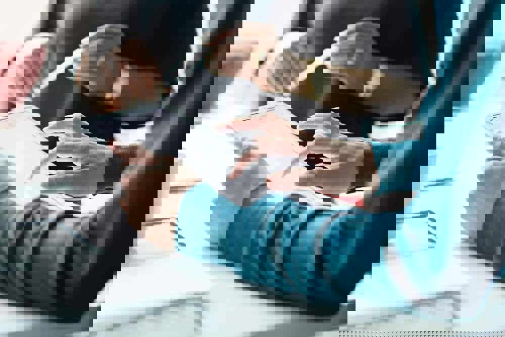 Close-up of co-workers standing at desk with laptop and talking