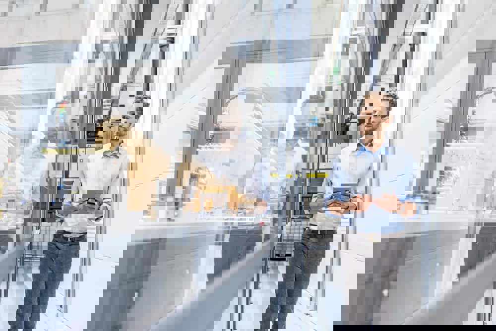 Businessman checking robots with digital tablet in high tech company