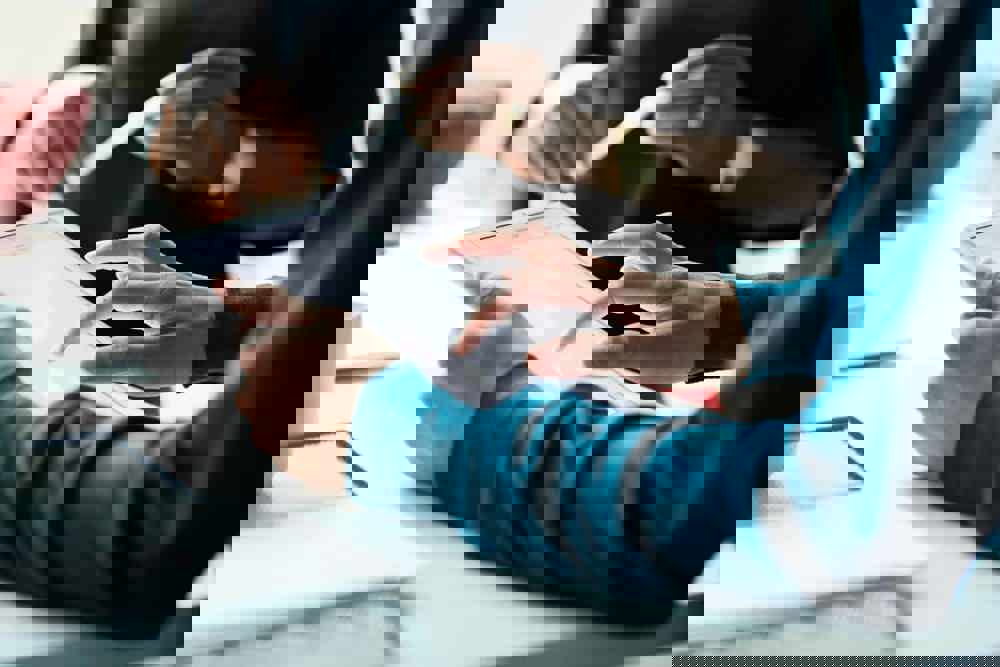 Close-up of co-workers standing at desk with laptop and talking (2)