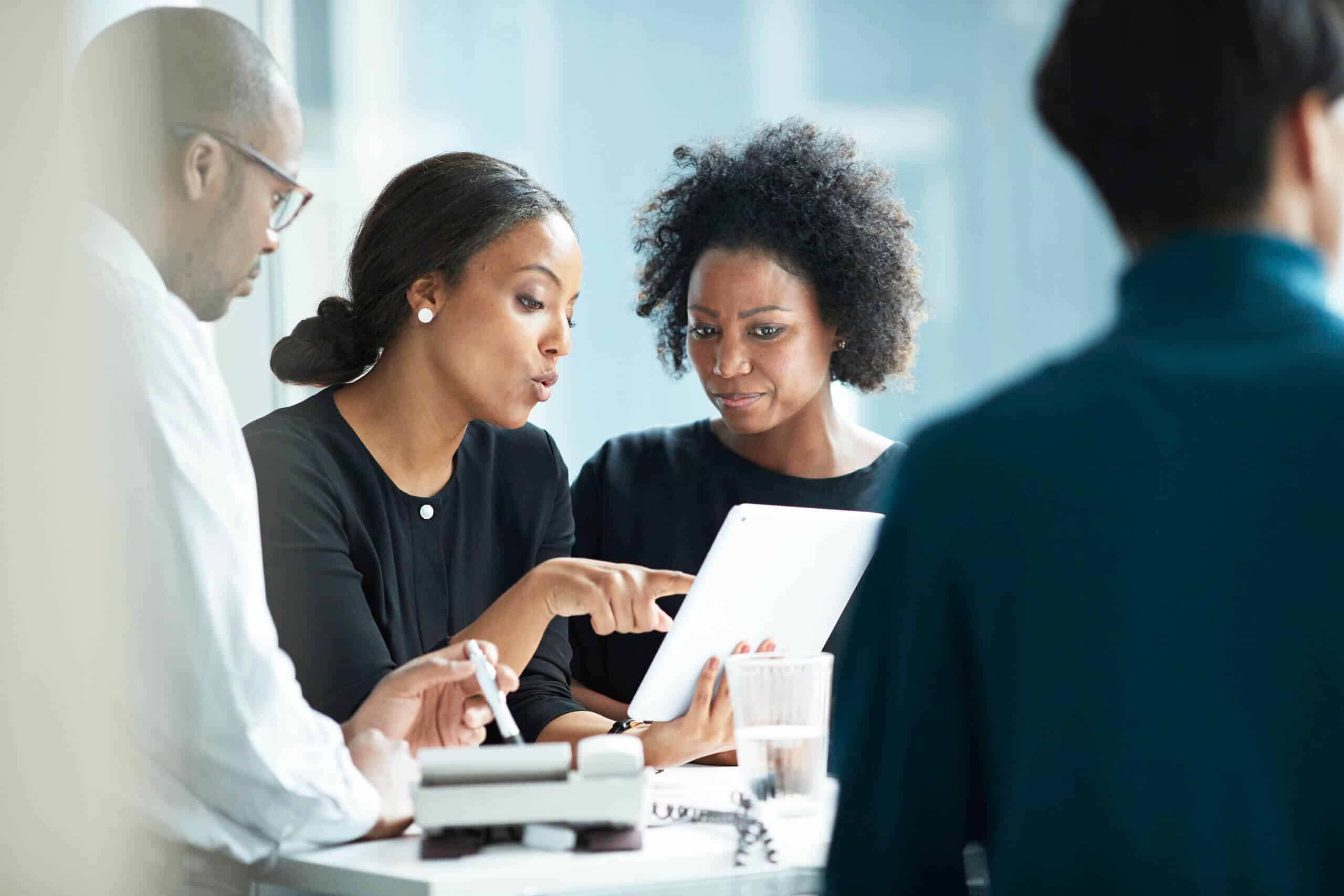 Group of co-workers standing around desk and having meeting