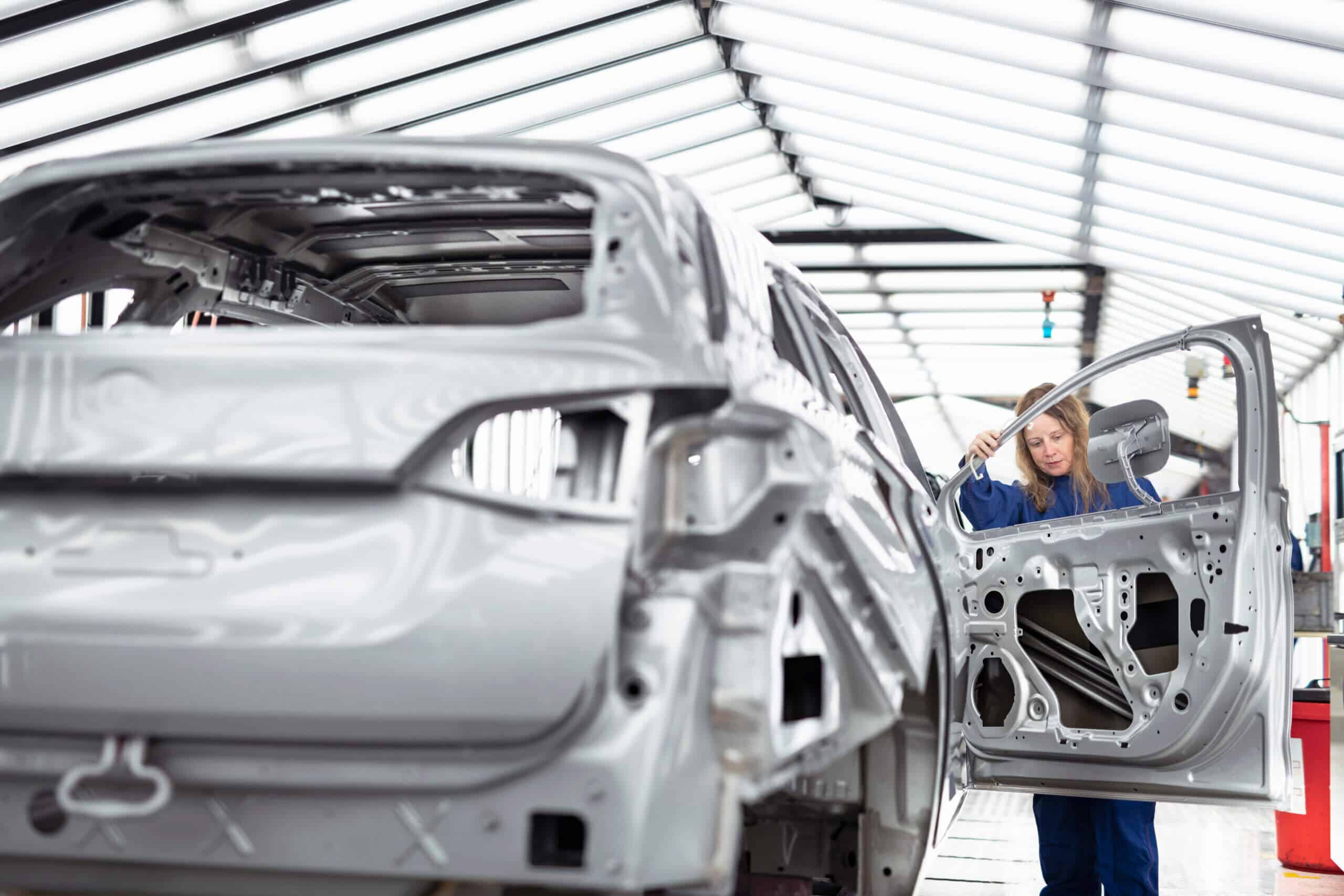 Worker inspecting car body in paint inspection area in car factory