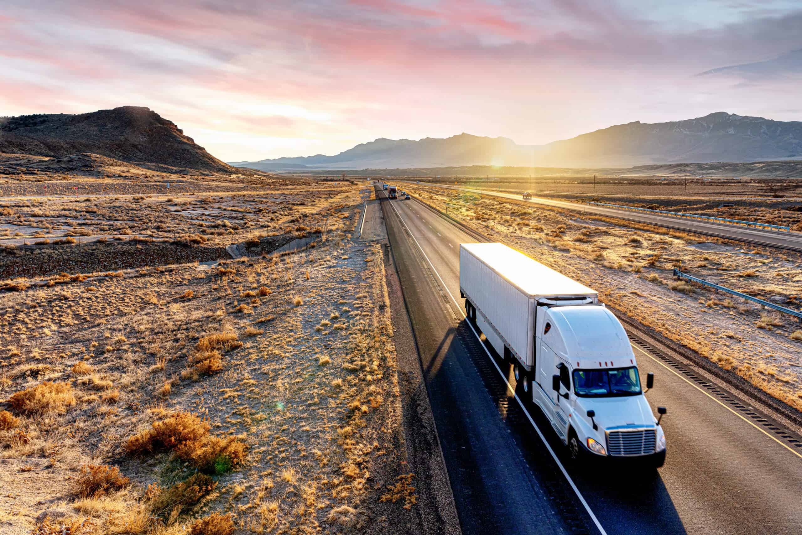 White Semi-Trailer Truck Heading down a four-lane Highway at Dusk