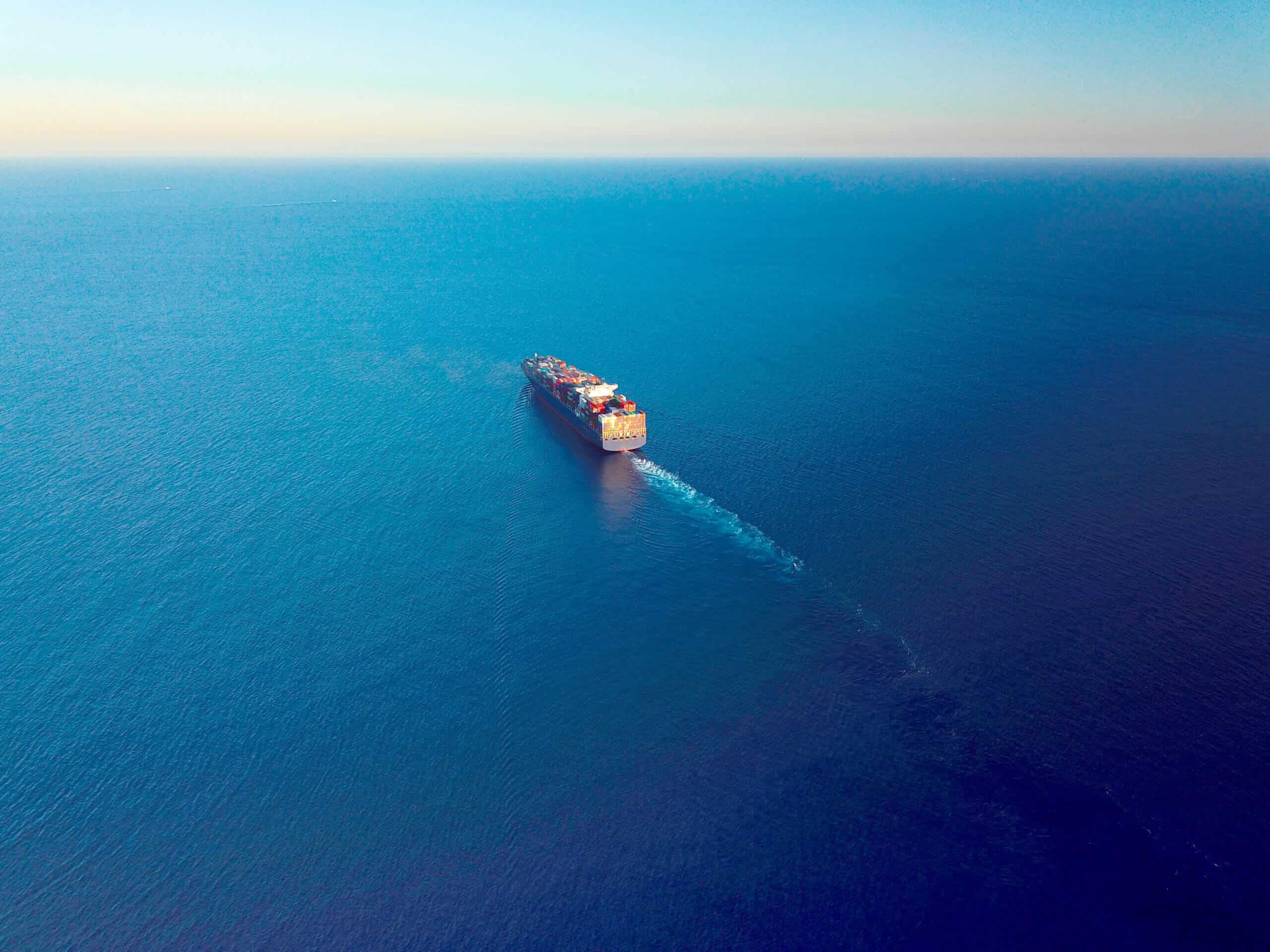 Aerial view of a cargo ship on the move in the middle of the sea.