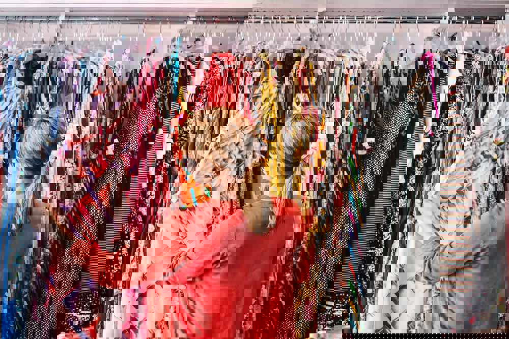 Woman looking at dress hanging on rack while standing at store