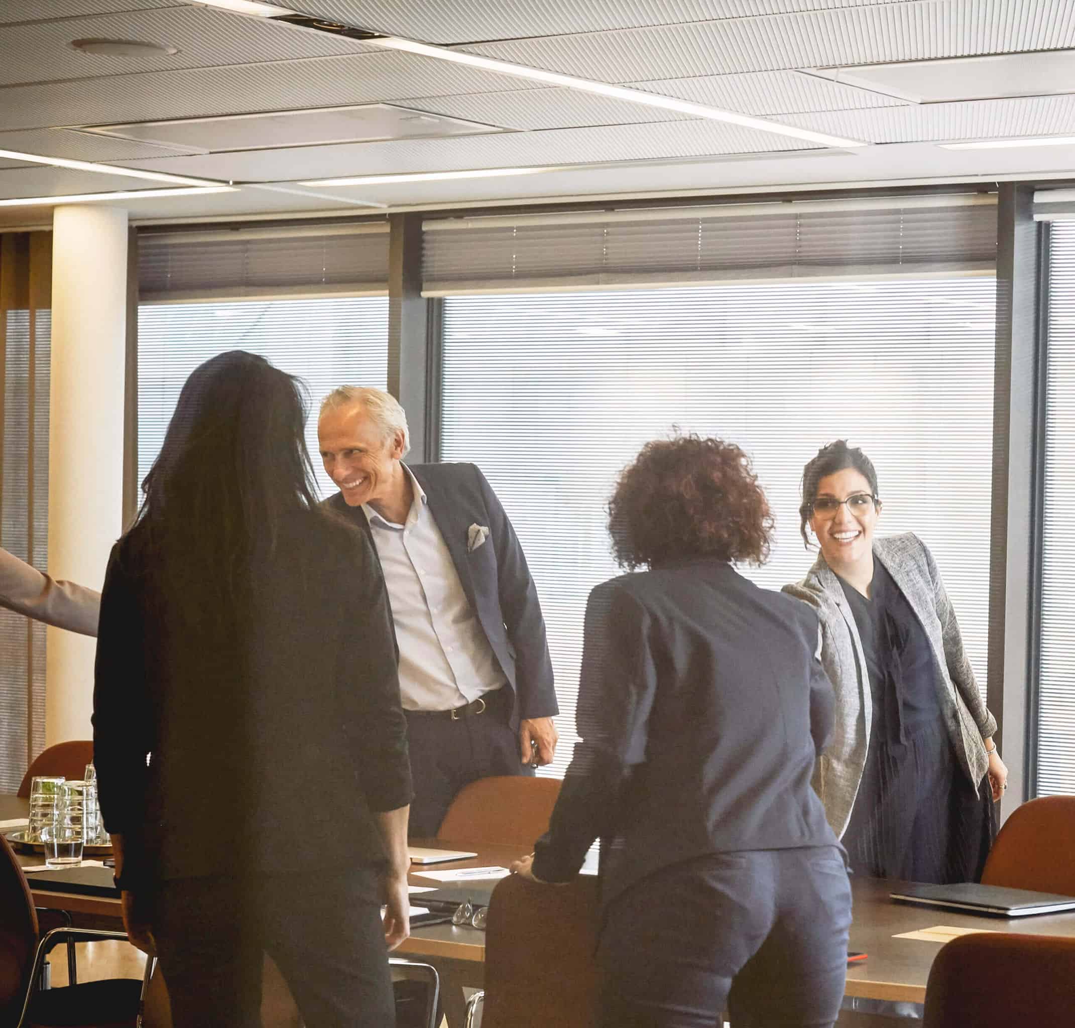 Smiling male and female lawyers shaking hands while greeting each other at board room in office (1)