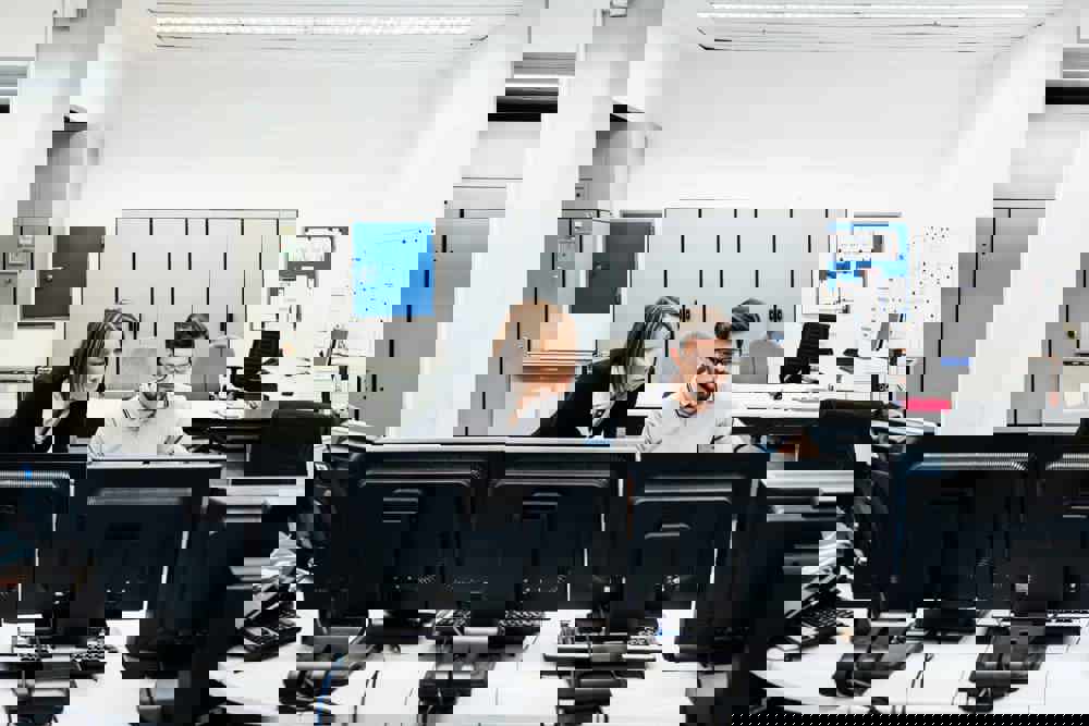 Operations Manager Assisting Colleague In Factory Control Room