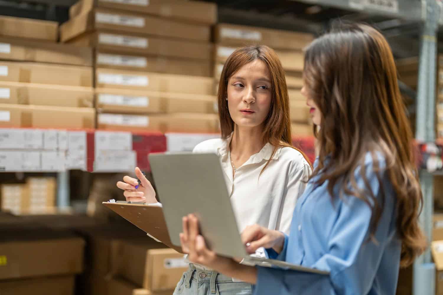 Supply chain managers reviewing inventory data and discussing scenario planning in a warehouse environment
