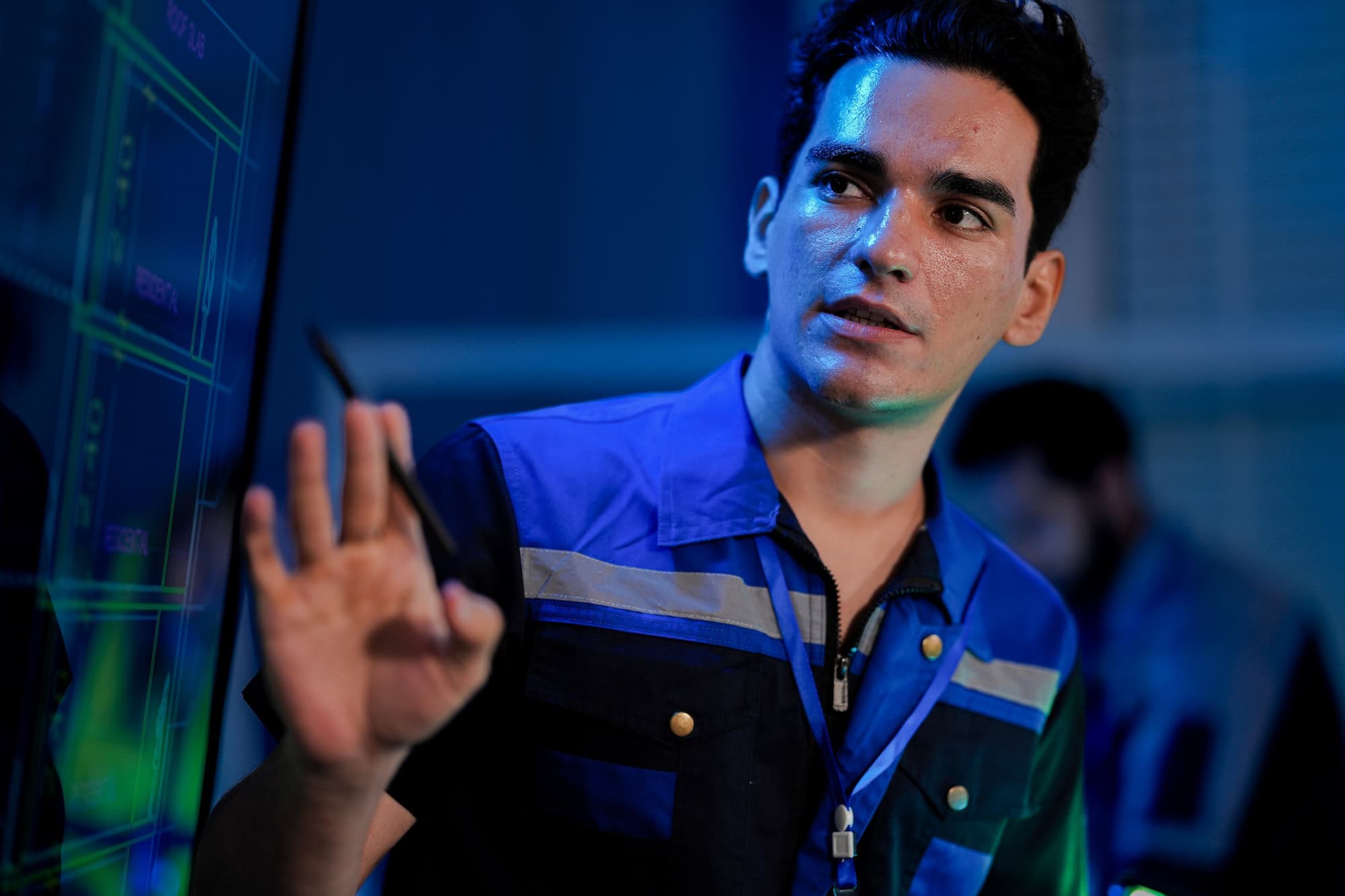 Manufacturing technician analyzing production data on a digital display during a control tower meeting.