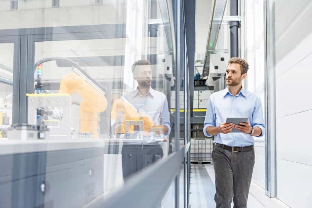 Businessman checking robots with digital tablet in high tech company Businessman checking robots with digital tablet in high tech company