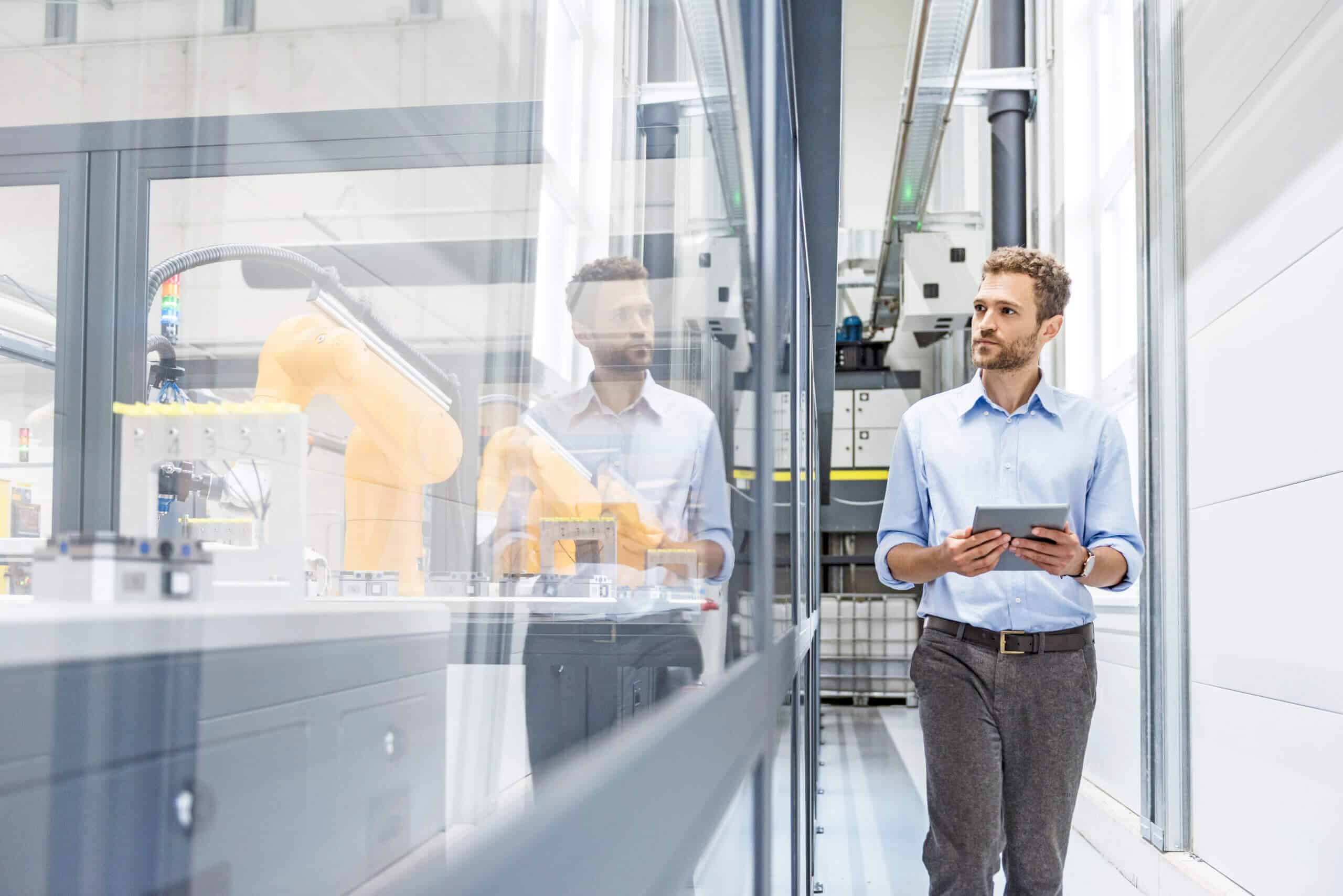 Businessman checking robots with digital tablet in high tech company