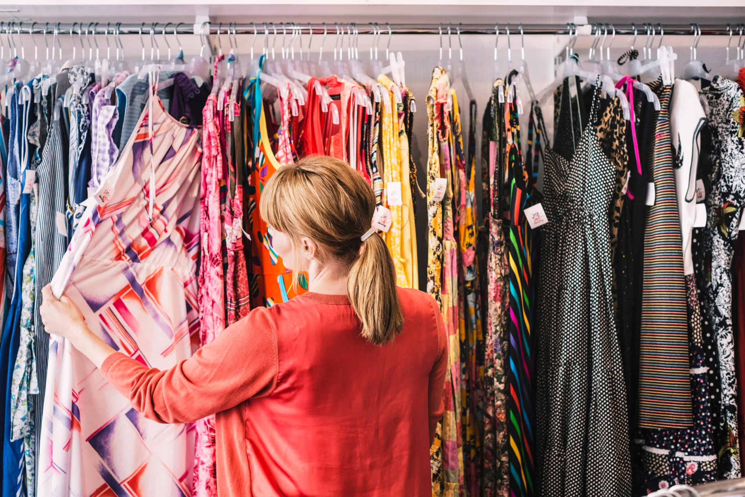 Woman looking at dress hanging on rack while standing at store