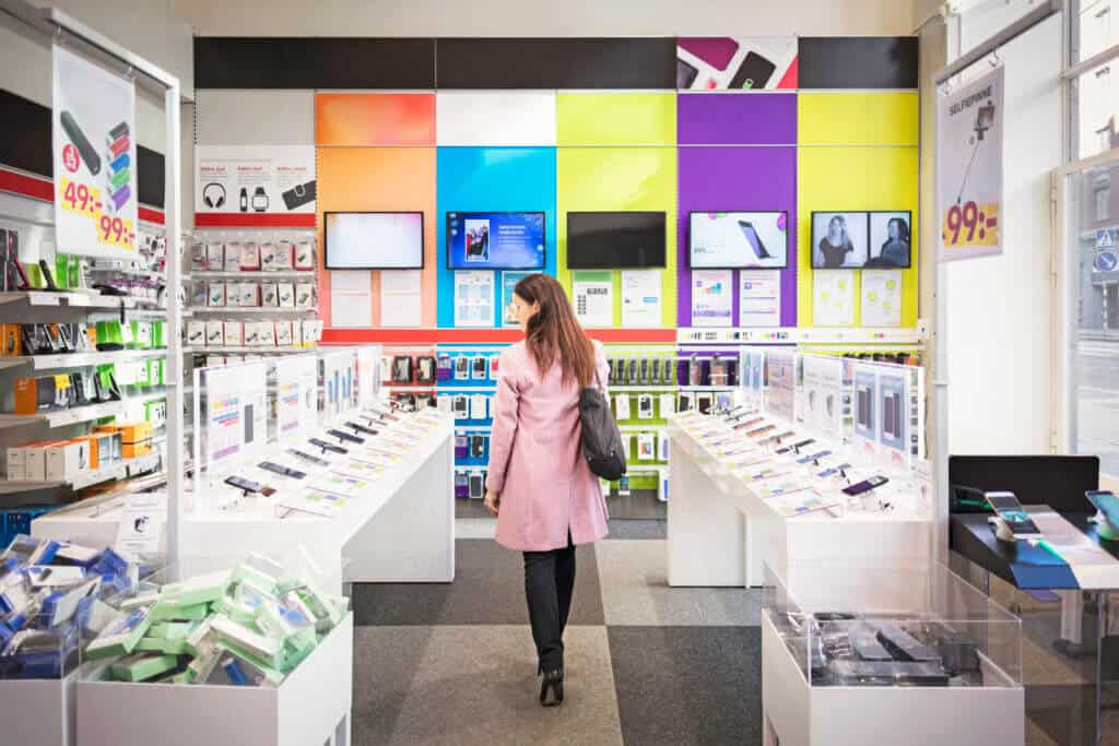 Rear view of female customer viewing smart phones in store Rear view of female customer viewing smart phones in store