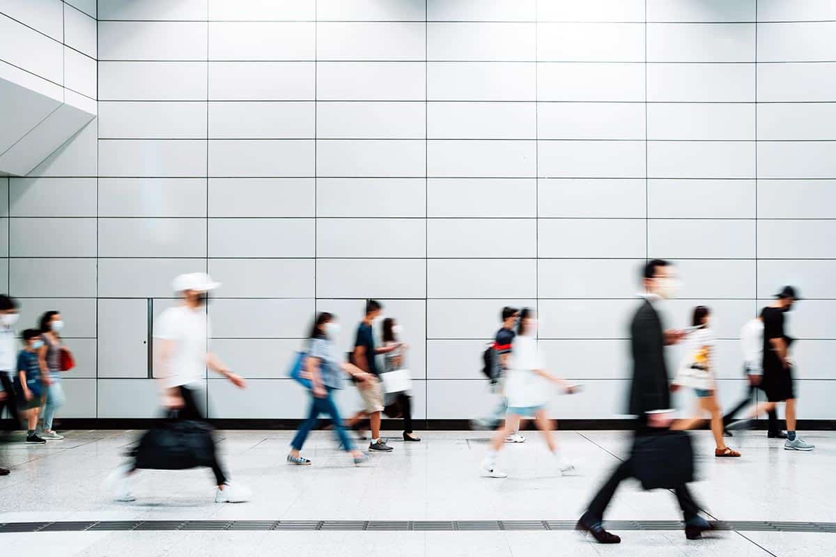 Blurred motion of a crowd of busy commuters with protective face mask walking through platforms at subway station during office peak hours in the city