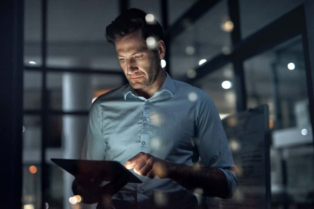 Business man, working and tablet of a employee doing digital, web and internet strategy planning. Corporate businessman and tech worker in the dark using technology to work on online and IT analytics 2023 IDC MarketScape: Worldwide Multi-Enterprise Supply Chain Commerce Network