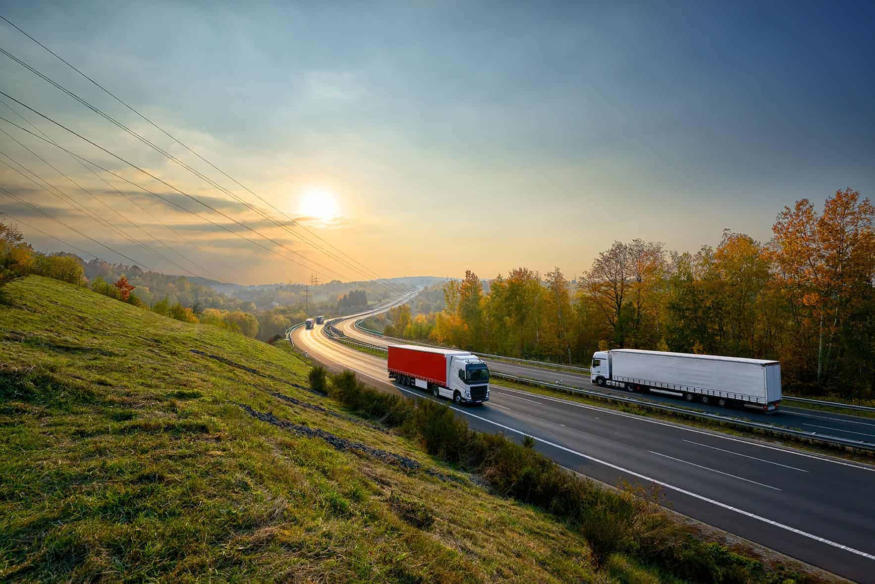 Trucks,driving,on,the,asphalt,highway,in,autumn,landscape,at
