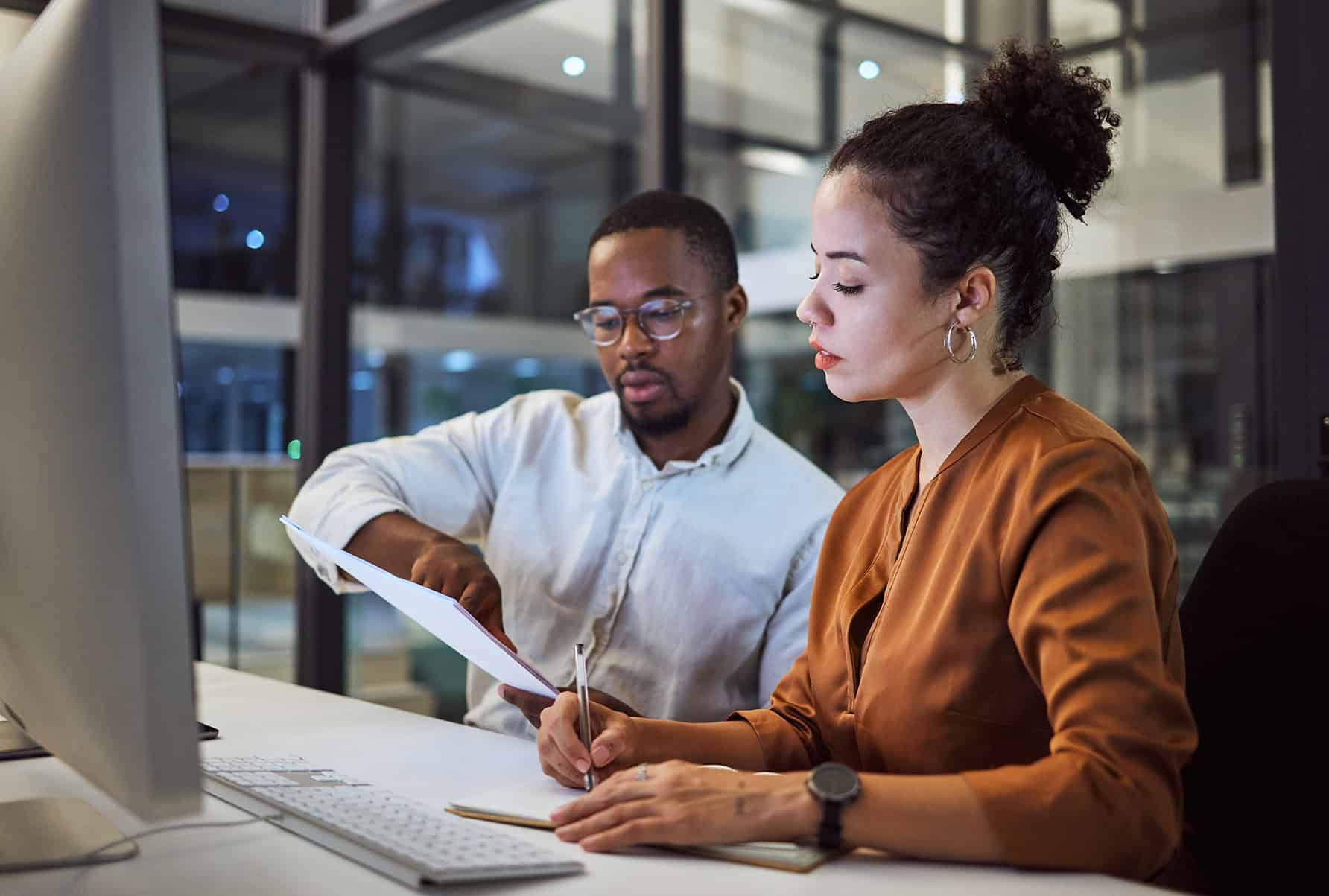 Teamwork In New York Office At Night, Business Document Reading Together And Professional Accounting Report. Black Man With Financial Audit, Showing Latino Woman Figures And Employee Collaboration